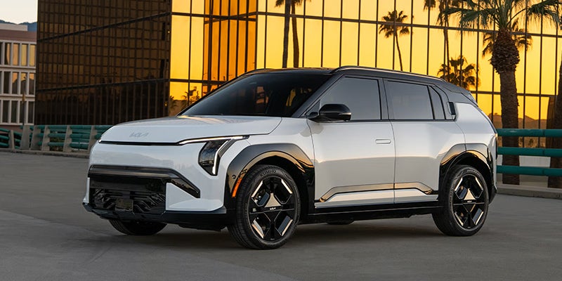 A 2027 Kia EV3, a subcompact all-electric SUV featuring a boxy, futuristic design, vertical LED headlights, and black-accented alloy wheels.